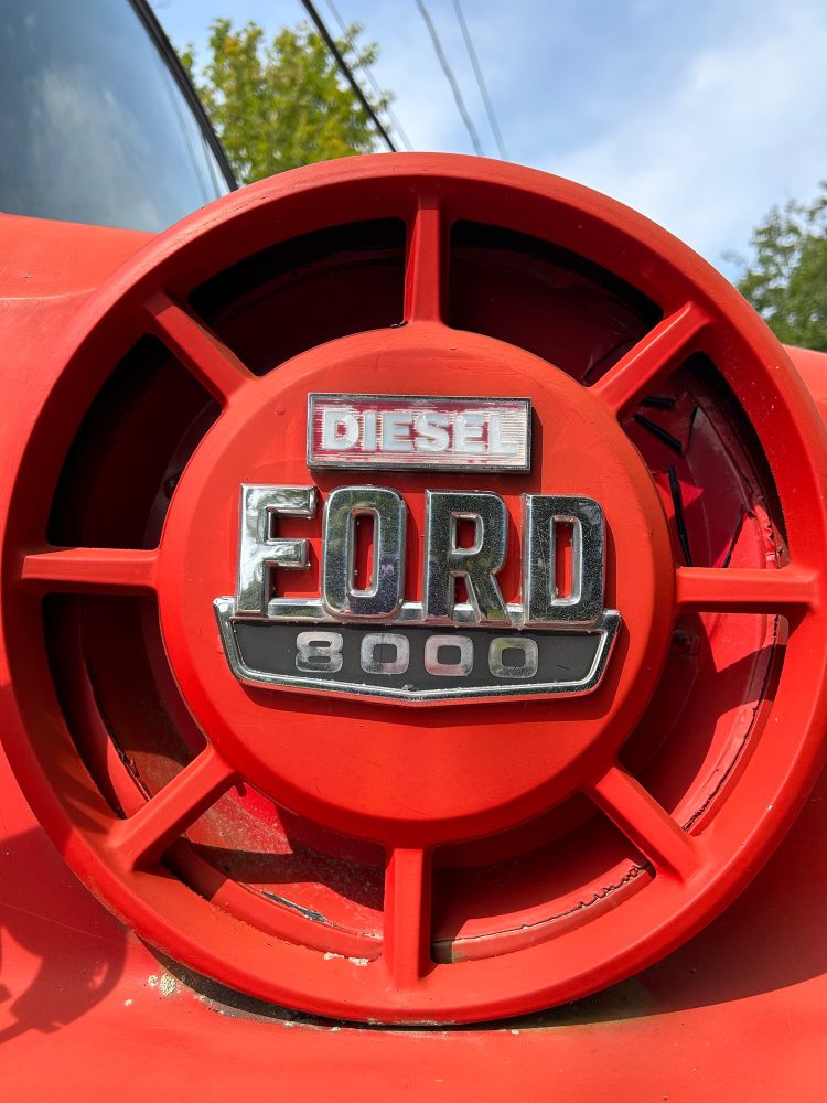 Emblem of a Ford 8000 Diesel truck. In red and chrome.