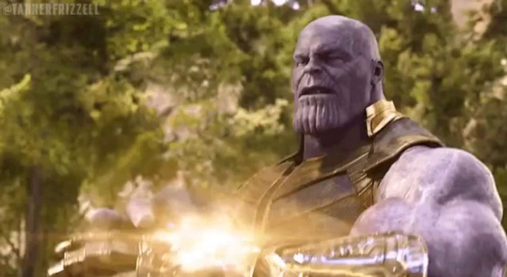 thanos from avengers infinity war is holding a gun in his hand and looking at the camera .