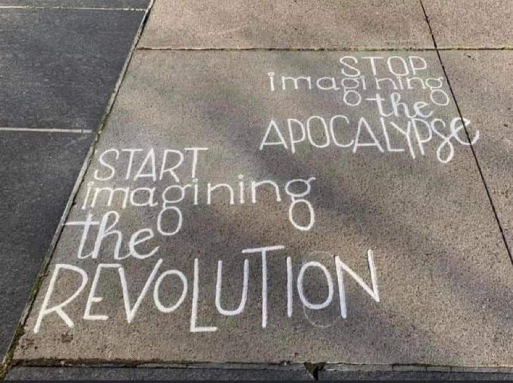 Sidewalk with chalked words as follows:
"Stop imagining the Apocalypse. Start imagining the Revolution."