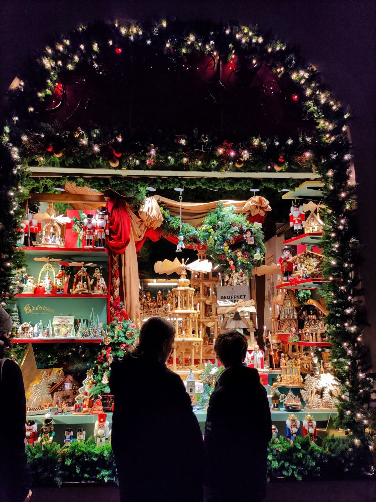 Silhouettes of two people standing in front of a Christmas shop window