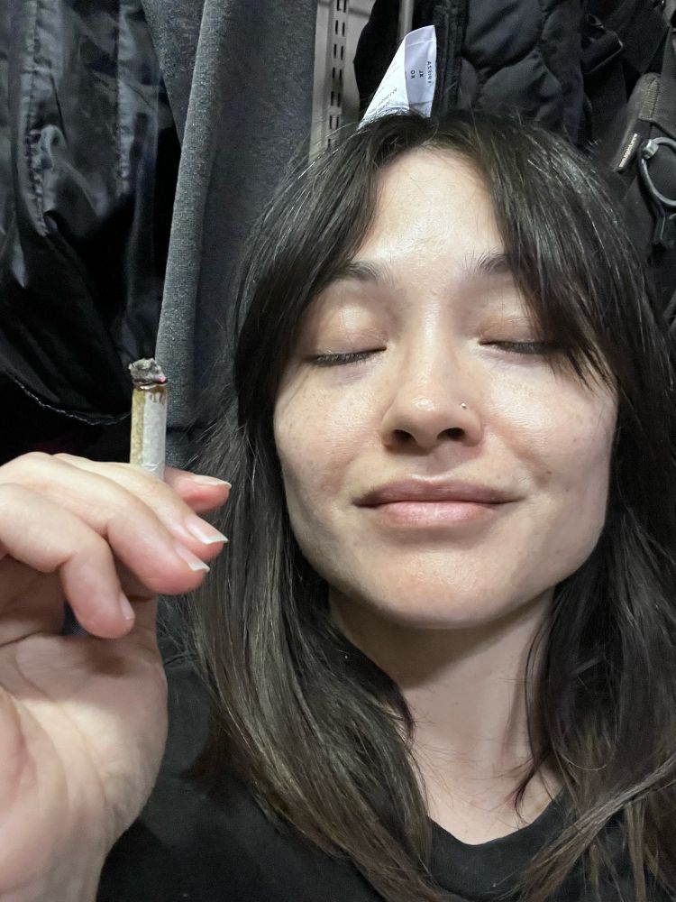 Selfie of me holding up a lit j with my eyes closed and a satisfied expression 