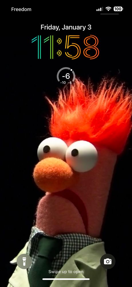Screenshot of an iPhone Lock Screen with Beeker from The Muppets looking shocked, as always, strongly lit against a black background. 