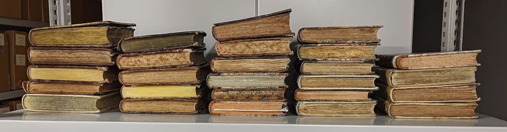 26 copies of a 17th century book, lying seen from the bottom edge. 