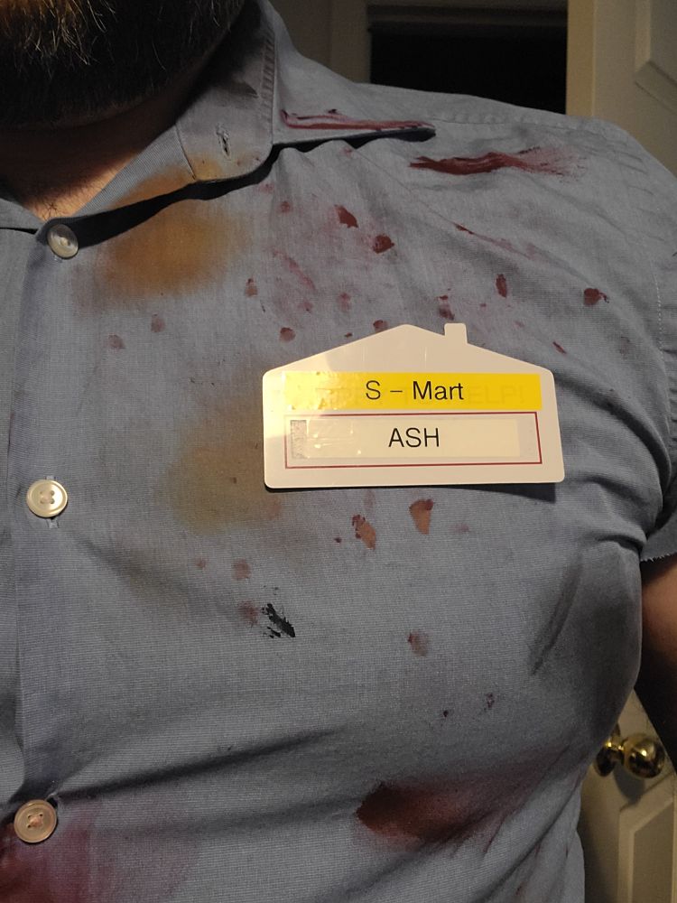 A close up of a bloody shirt wearing a name tag that says "S-Mart. ASH" 