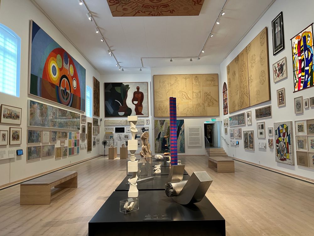 The international gallery of the Skissernas museum, showing three painting-covered walls with sculptures occupying the centre of the room. Works include large sketches by Matisse, public murals by Delaunay, and ceramics by Léger.