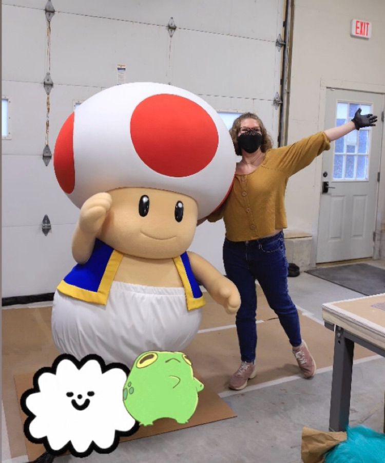Giant mushroom boy in a vest standing next to woman in yellow shirt