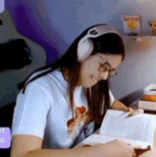 a woman is wearing headphones and reading a book .