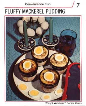 Recipe card for "Convenience Fish - Fluffy Mackerel Pudding" showing photo of a plate with four cups of tan stuff with sliced hard boiled eggs on top.  Photo also shows two candles and a basket of eggs.