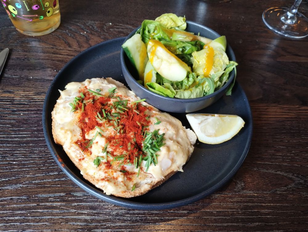 Grey plate with a big slice of sourdough topped with crab & prawns in another creamy sauce, garnished with lots of chives and paprika. A wedge of lemon on the side, and a bowl of cucumber/apple/little gem salad with a yellow dressing which I THINK called itself pineapple ketchup 🤔