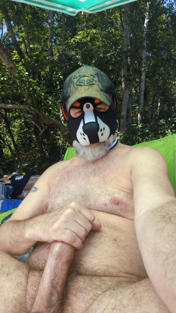 Naked human dog at the beach, holding his boner. He's wearing a nastypig cap that has hundreds of loads on it.