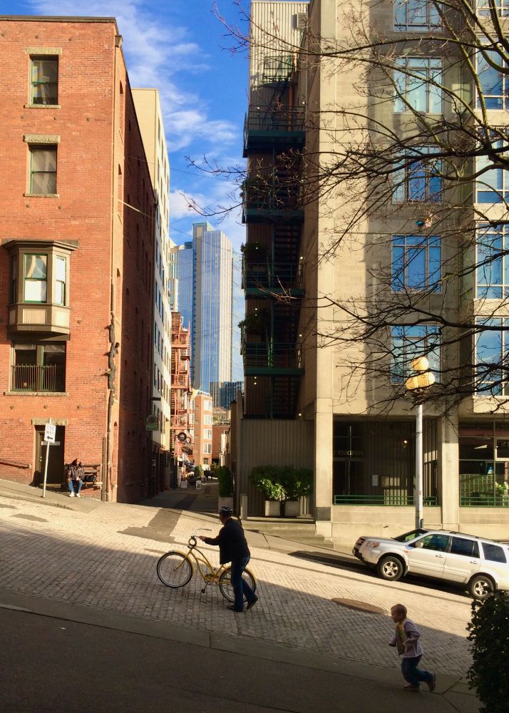 Seattle street, showing man pushing bike up steep slope, little boy running