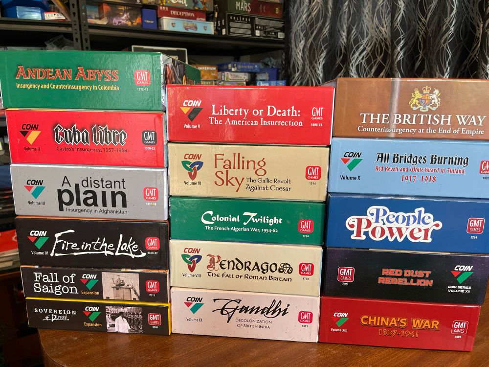 Three stacks of boardgames, a full collection of the COIN games.