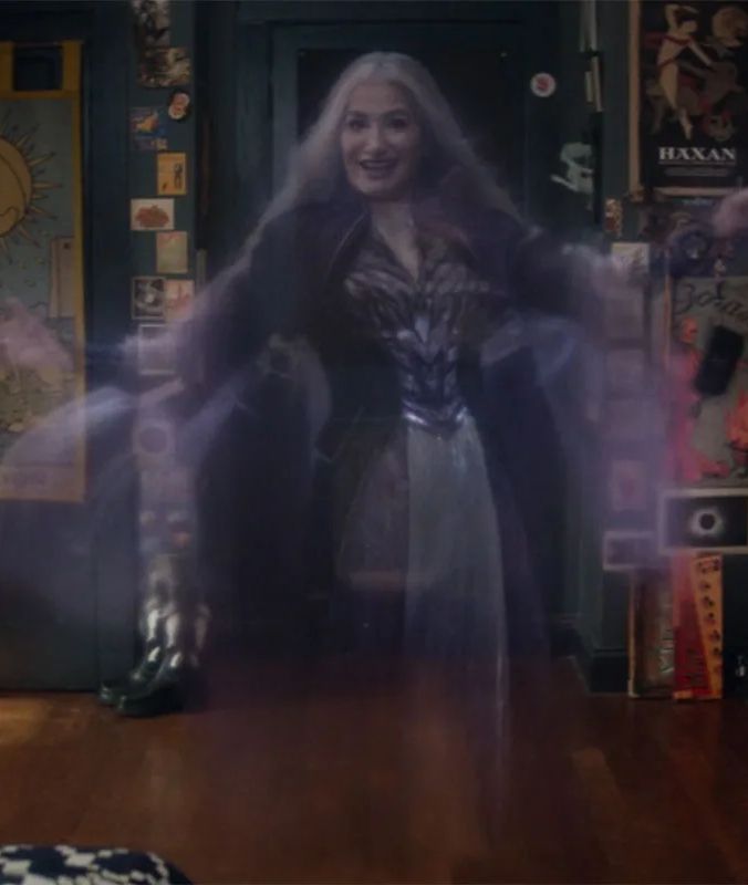 An image of Agatha Harkness as a ghost in episode nine of Agatha All Along. She is standing in Wiccan's room with her arms spread wide and smiling.