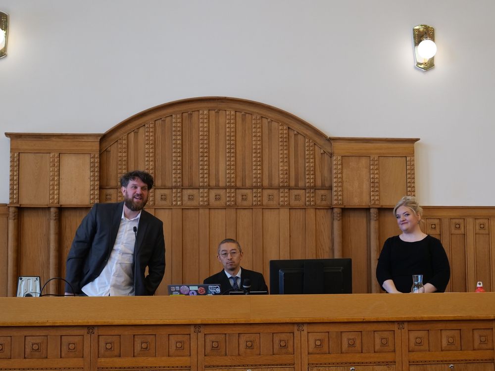 Doctoral defence, with opponent, custos and me - opponent speaking to the audience and me looking at the opponent.
