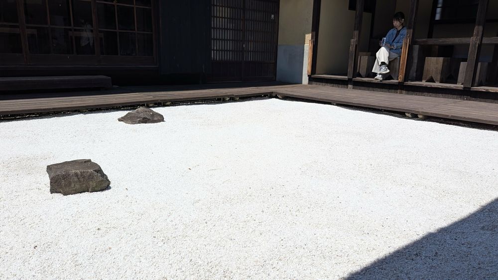A dry "zen" garden inside the inner courtyard of a Japanese house. A woman is sitting in the background and is looking at the rocks and sand.

However, there is more than meets the eyes, but you'll have to go there to find out. (it's an artwork by Leandro Erlich on Megijima in Japan)