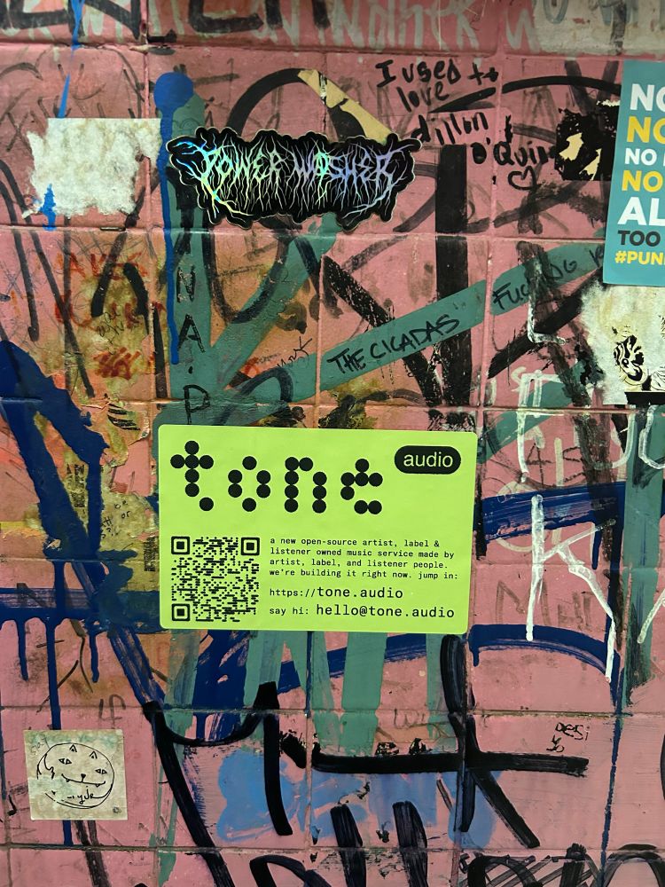 tone.audio promotional sticker, placed on a wall