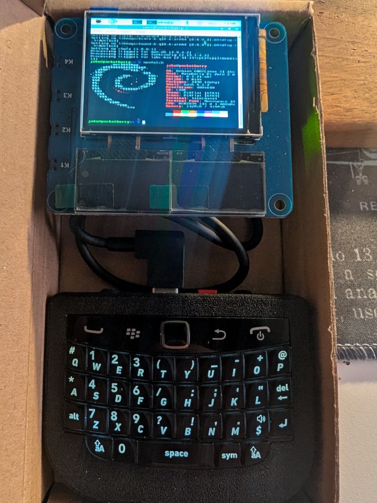 2 inch LCD screen showing a Linux terminal connected to a BlackBerry keyboard, inside a box