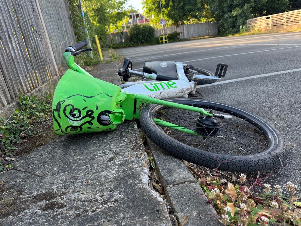 Someone had ditched this Lime public e-bike in a car park, and had painted a dying/shocked face on the front of its basket. 