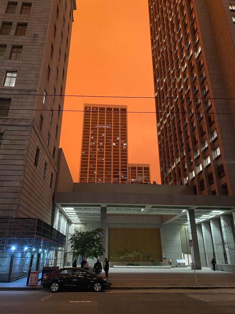 A street view of an office building in San Francisco against a shockingly orange sky. 
