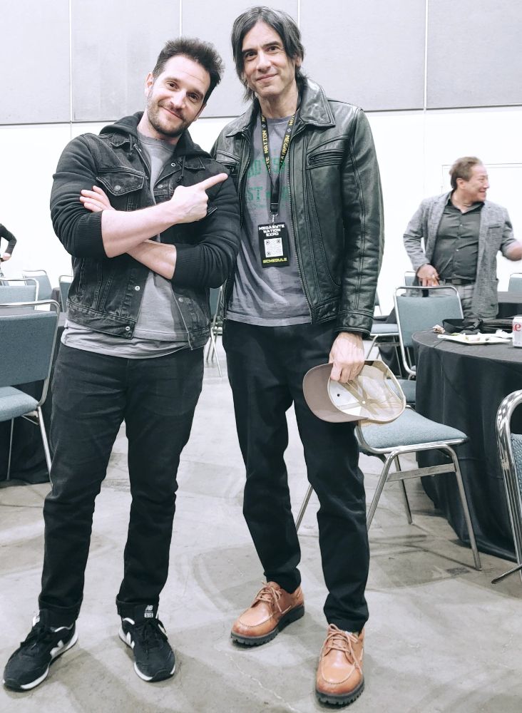 Nick Apostolides (current Resident Evil 2 &4 Leon voice actor and motion capture performer) and Jamisin Matthews legacy Leon Kennedy face model (photographic) and reference for the animated Resident Evil movies and in non-primary games Operation Raccoon City together standing looking into camera. Jamisin in leather jacket and Nick in black denim. Daniel Pesina from Mortal Kombat smiling in background.