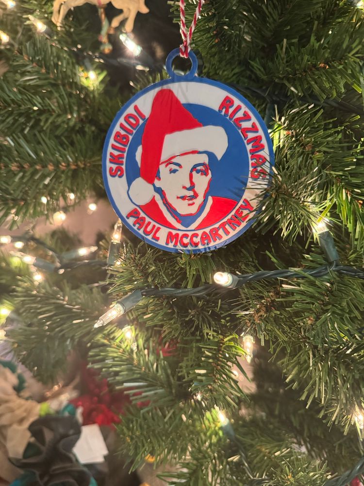 A 3D printed Christmas ornament with a picture of Paul McCartney in a Santa hat and the words “Skibidi Rizzmas, Paul McCartney”