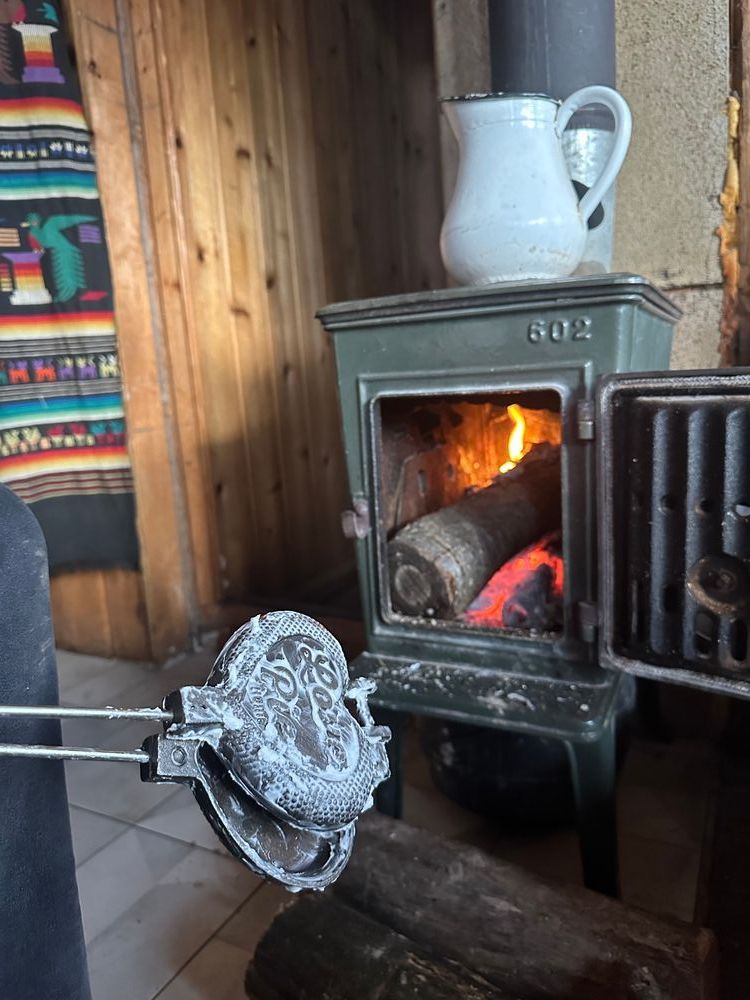 the pudgy pie makers are seen here in front of a green wood fire stove. the pie makers are covered in Crisco.