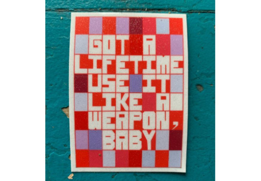picture of a colorful red and purple sticker that reads "got a lifetime use it like a weapon, baby" in white text.