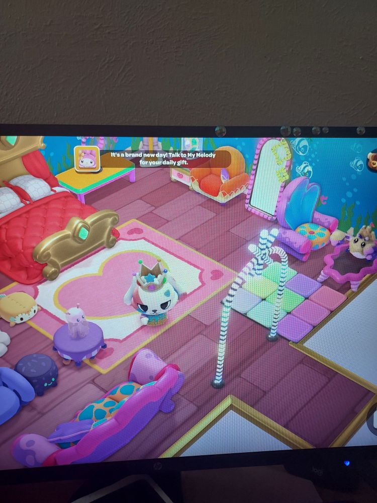 photo of a computer monitor that is displaying Hello Kitty Island Adventure. The room is very cool and epic and full of a lot of different variety of furniture like a dance mat and underwater wallpaper.