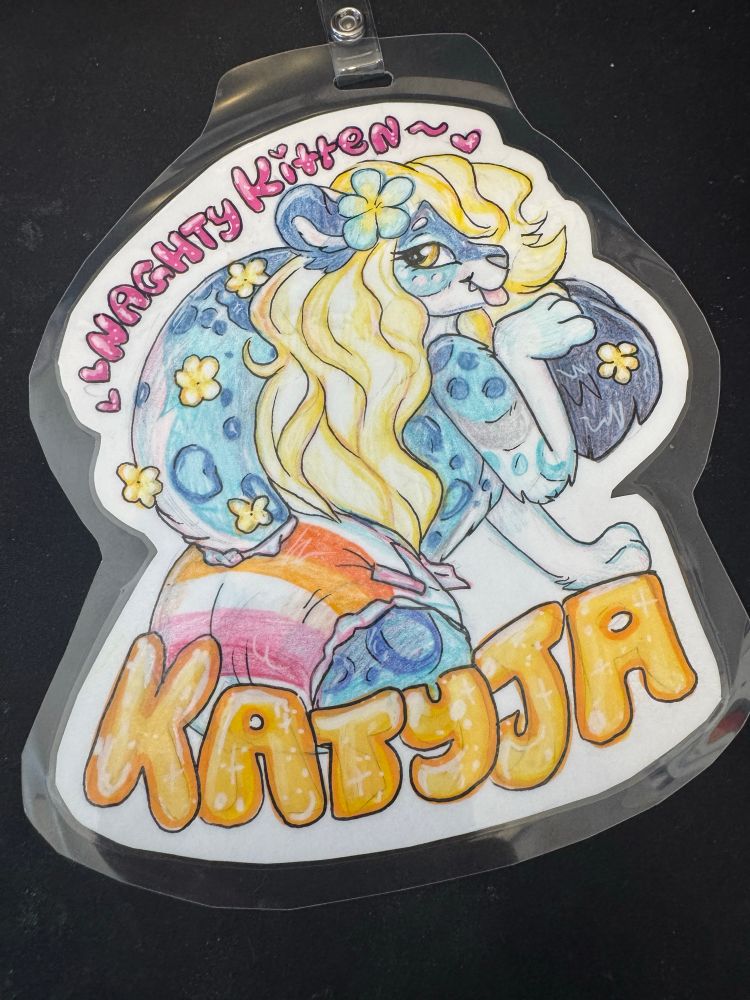 Katyja with her tail raised revealing a diaper with the lesbian pride flag printed on it. She is looking at the viewer, body turned away, and licking her paw flirtingly 