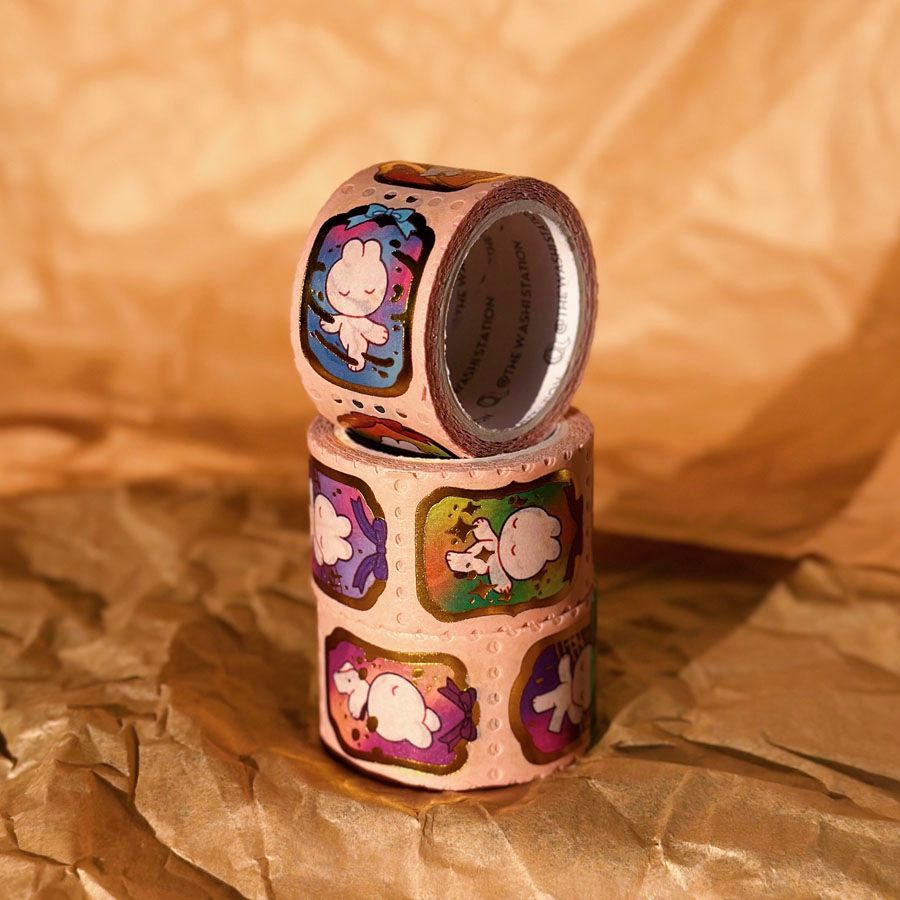 Photo showing the finished washi tape. The frames and particle effects from the sketches are finished with gold foil and the bunnies each have rainbow-colored background. You can tear off each frame like a stamp.