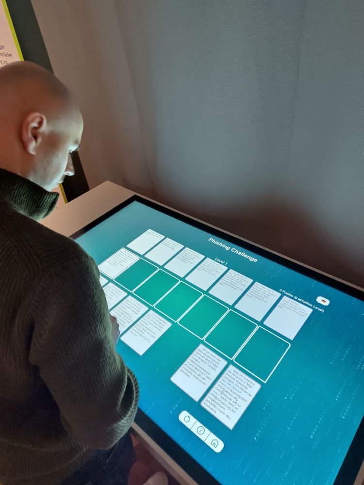 Eine Person spielt das NoPhish-Cardgame an einem Touchtable in der Ausstellung.