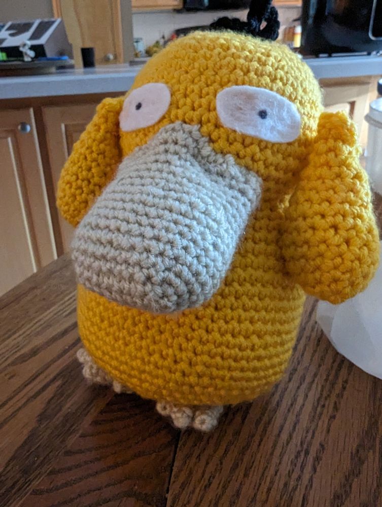 A crocheted Psyduck facing the camera