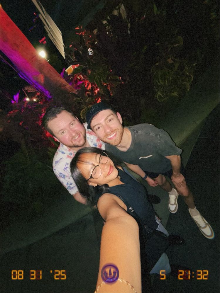 Lucas and 2 friends taking a .5x selfie in front of a tree with purple and orange Halloween lighting