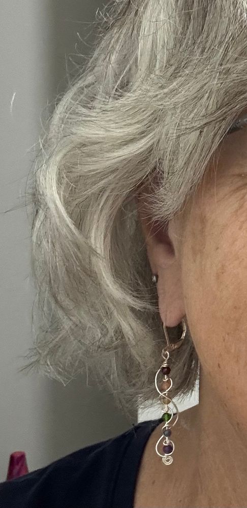Rainbow beads wrapped in silver to make a dangle earring, shown hanging from my ear!