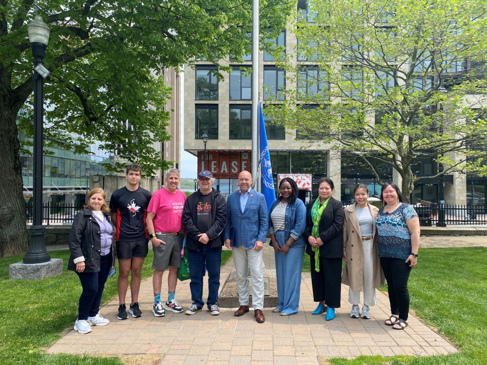 A photo of Mayor, Council Members and community members marking the International Day of Play with a municipal flag raising on June 2. 