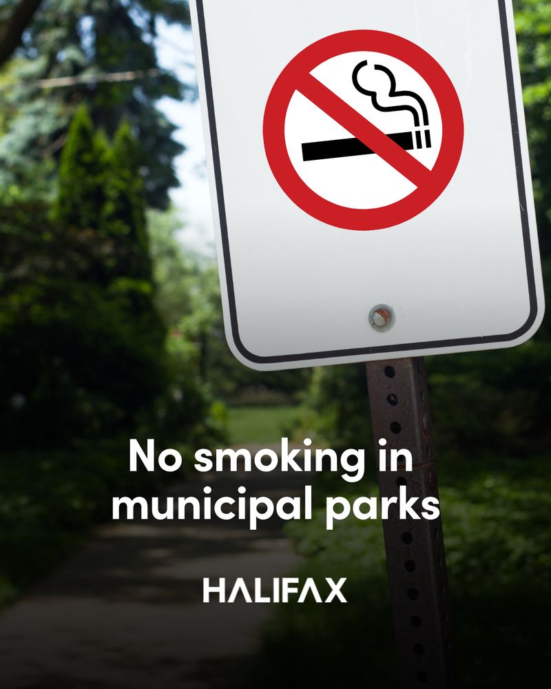 A no smoking sign with a park in the background and text that reads 'No smoking in municipal parks.'