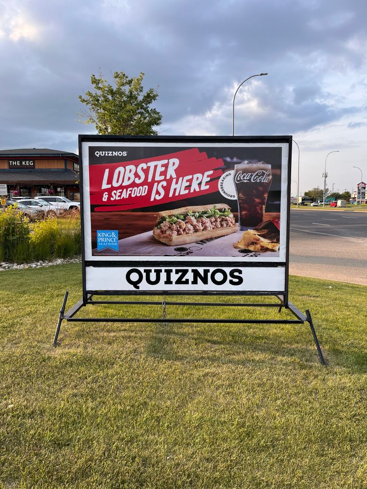 A road side marketing sign showing a Quiznos lobster & seafood sandwich.
