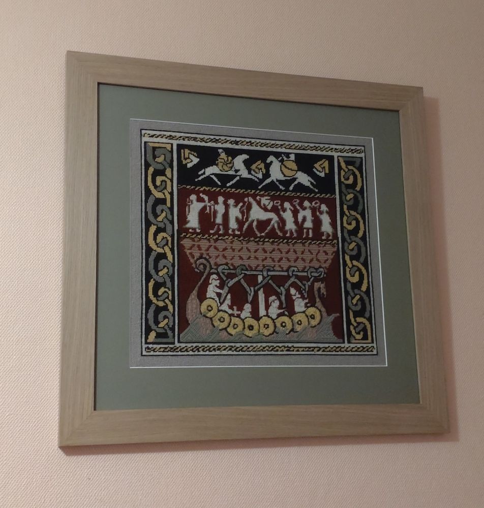 A framed needlepoint picture of Pictish men