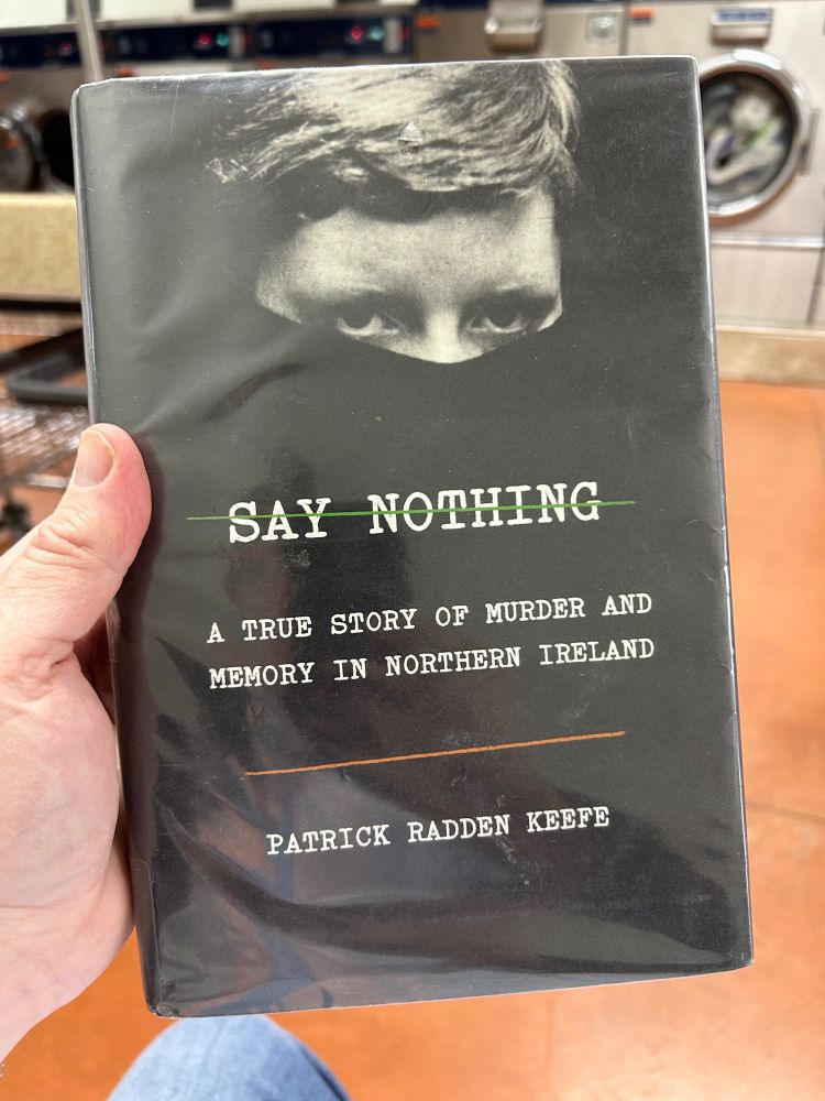 Me holding a copy of the above-mentioned book while at the laundromat.