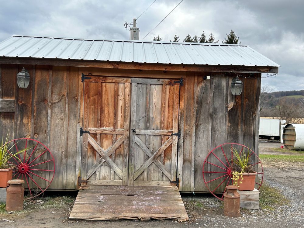 The unstaffed mini-store at Kriemhild Creamery.  A wooden shack with a tin roof and closed wooden double doors that need to be pulled open