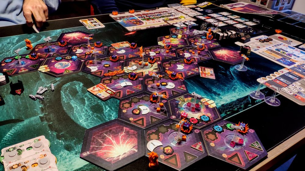 La photo montre le plateau centrale du jeu de société Voidfall. Un joli gloubi-boulga de miniatures de vaisseaux spatiaux et de pions variés.