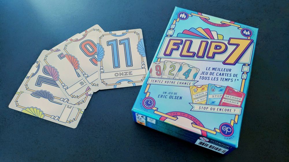 Photo du jeu de carte Flip 7. La belle boîte foil et quelques cartes.