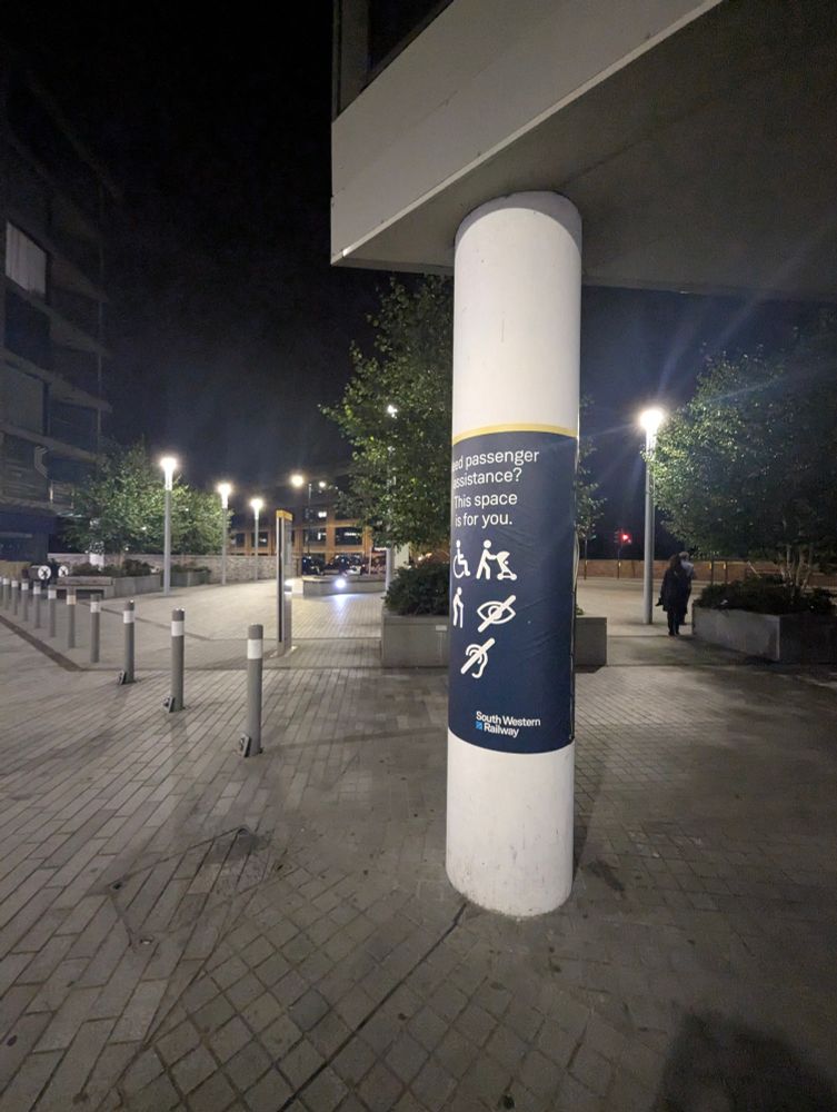 A beam holding up a building I guess outside Twickenham station. It says "need passenger assistance? This space is for you"