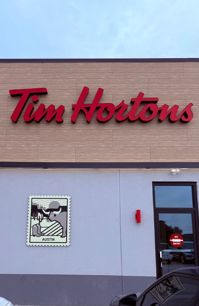 A photo of the outside of the new Tim Horton’s. With an “Austin” sign on the side of the building. 