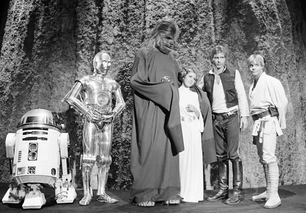 A group photo of R2, C-3PO, Han Solo, Luke Skywalker, Princess Leia, and Chewbacca from the Star Wars Holiday Special.