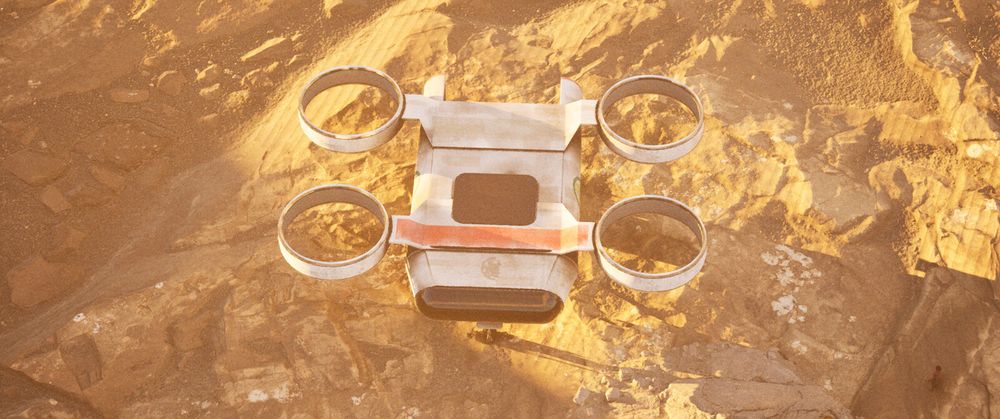 An aerial shot captures a futuristic, boxy hovercraft with four large, circular thrusters (two on each side) seemingly landed or hovering just above a rugged, sandy, or rocky orange-brown terrain. The vehicle itself is light-colored, with some orange or reddish accents on its body. The ground below is uneven and textured, suggesting a desert or an alien planet. The lighting indicates strong sunlight, casting sharp shadows and highlighting the rough surface of the terrain.