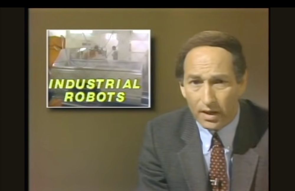 1980s newscaster with a graphic that says "industrial robots"