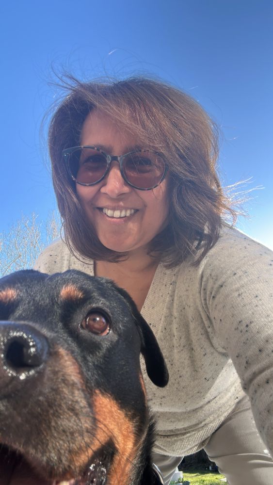 Woman and Rottweiler against a clear blue sky. 
