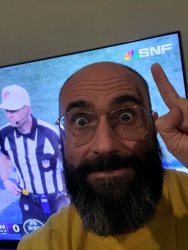 A picture of me in front of a TV pointing at a logo on the screen that says, "SNF"