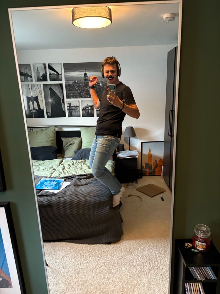 Ich, wie ich auf der Kante von meinem Bett mit leicht gebeugten Knien stehe. Auf dem Bett liegt die Platte von Lorde. Ich trage Airpods und bin sehr glücklich. 